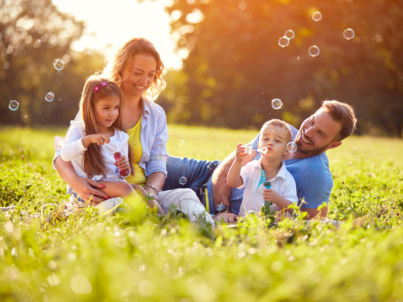 family blowing bubbles in grass